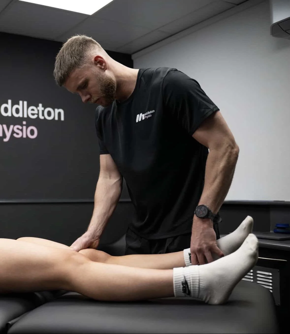 A physical therapist performs a treatment on a patient's leg in a physiotherapy clinic.