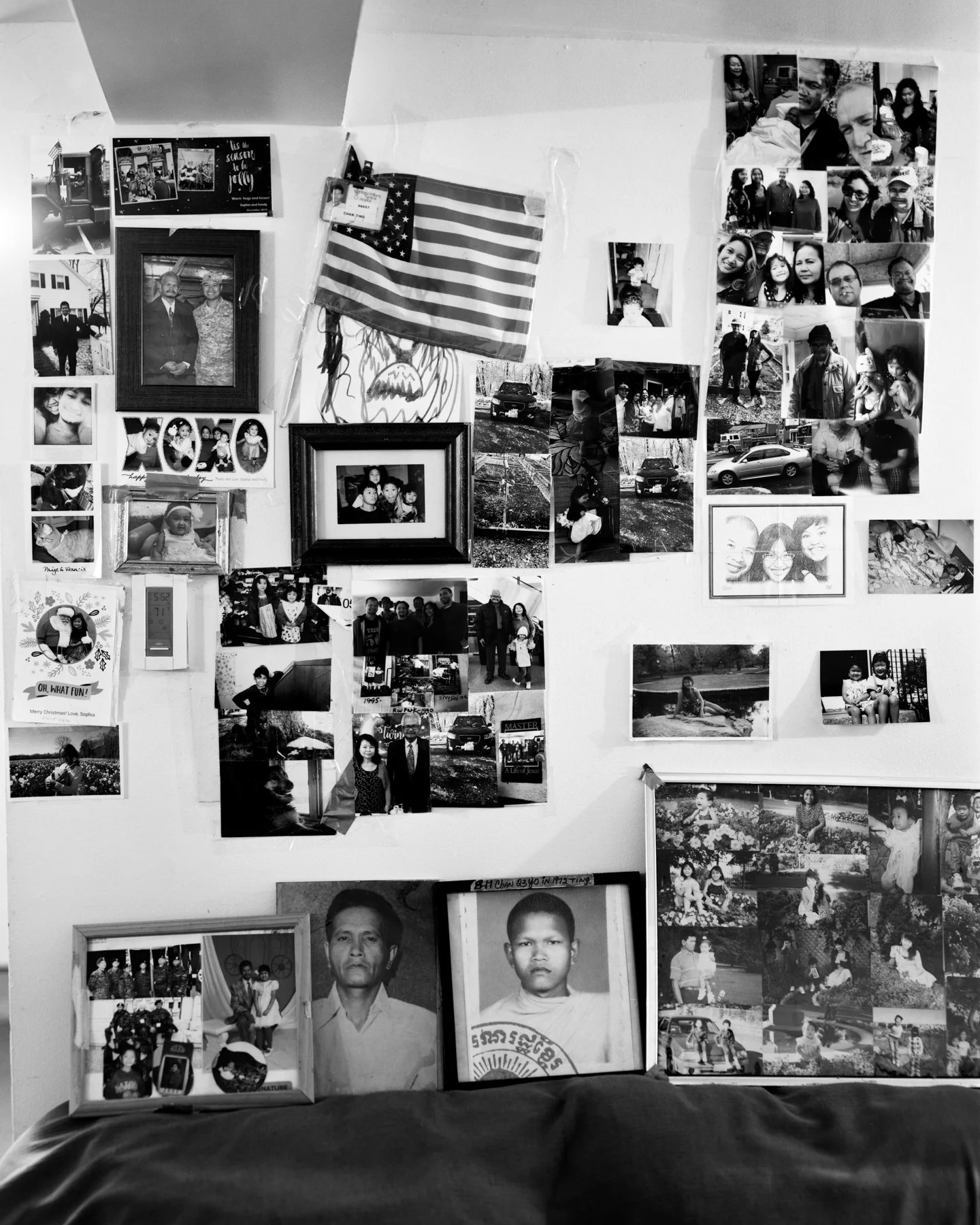 A wall decorated with numerous black-and-white family photographs, a small American flag, and some framed pictures, creating a collage of memories.