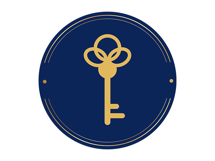 A circular emblem with a dark blue background, featuring a gold key with a decorative bow in the center. Anita McGovern Realty