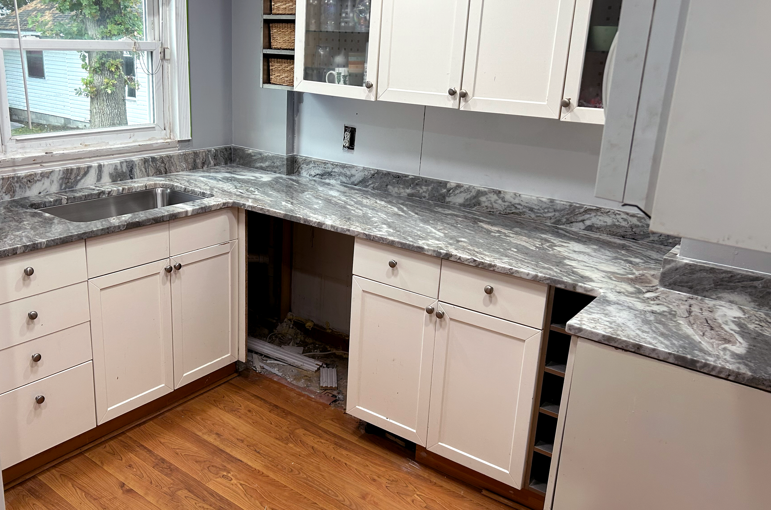 Stonecrafters marble countertop and double sink installation nearing completion in a white kitchen