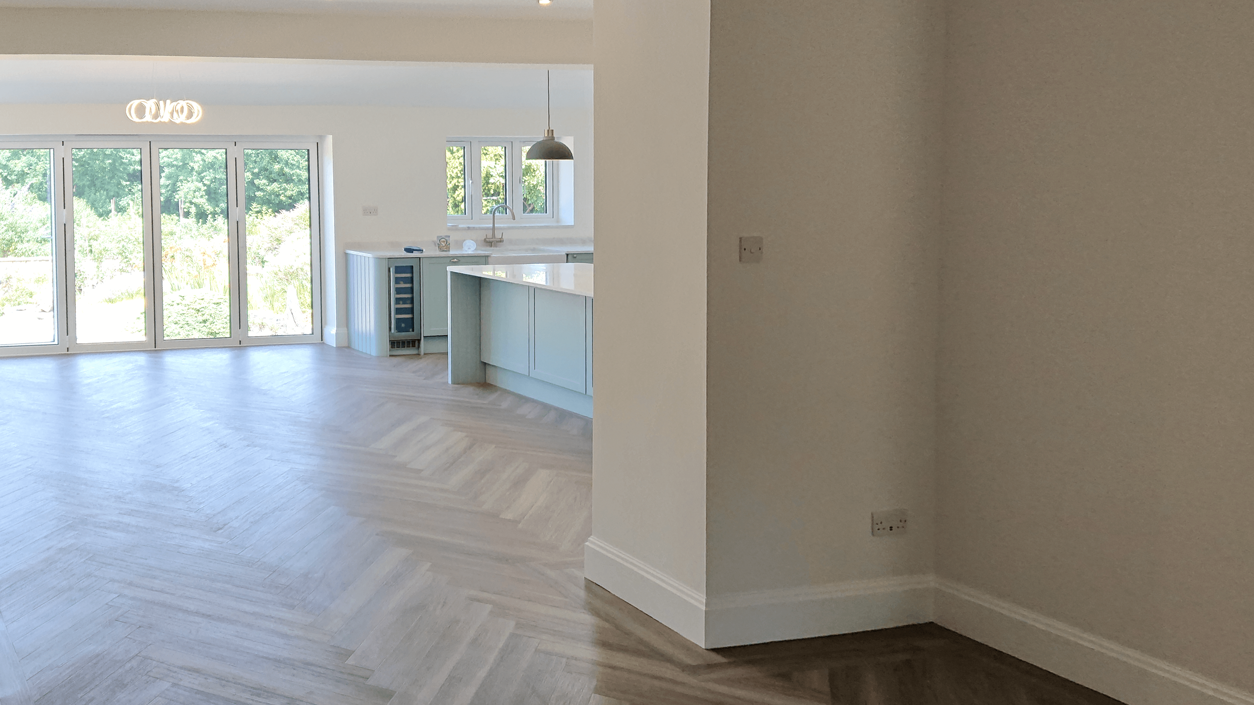 Hallway  in Westbury-on-Trym, Bristol leading to a luxury kitchen and large french doors leading outside. Light wood flooring.