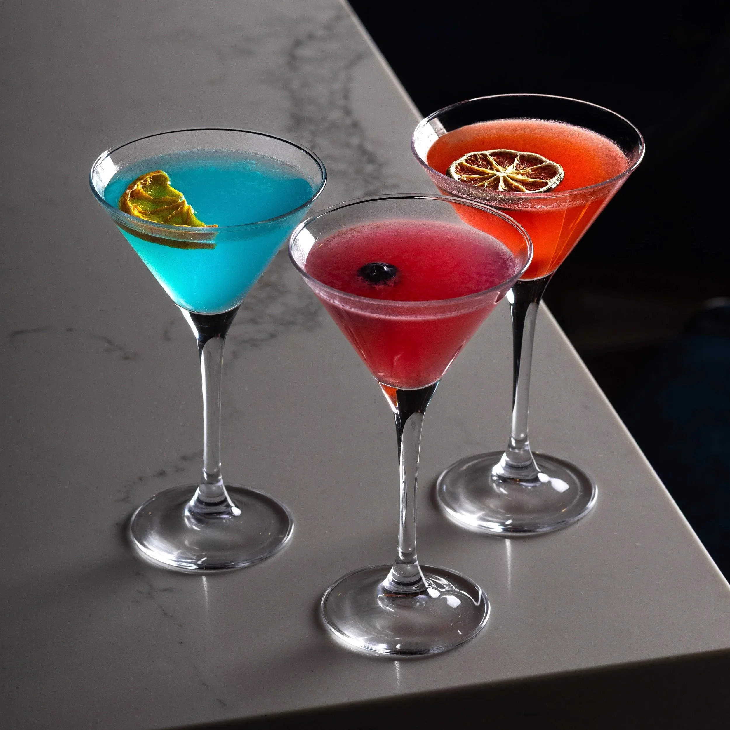 Southside Shake's three colourful Tiny Tini cocktails in martini glasses with garnish on the marble bar top.