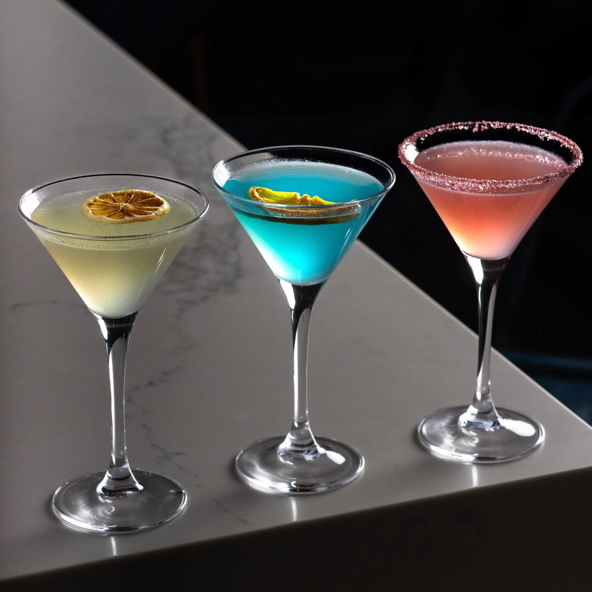 Southside Shake's three colourful Tiny Tini cocktails in martini glasses with garnish on the marble bar top.