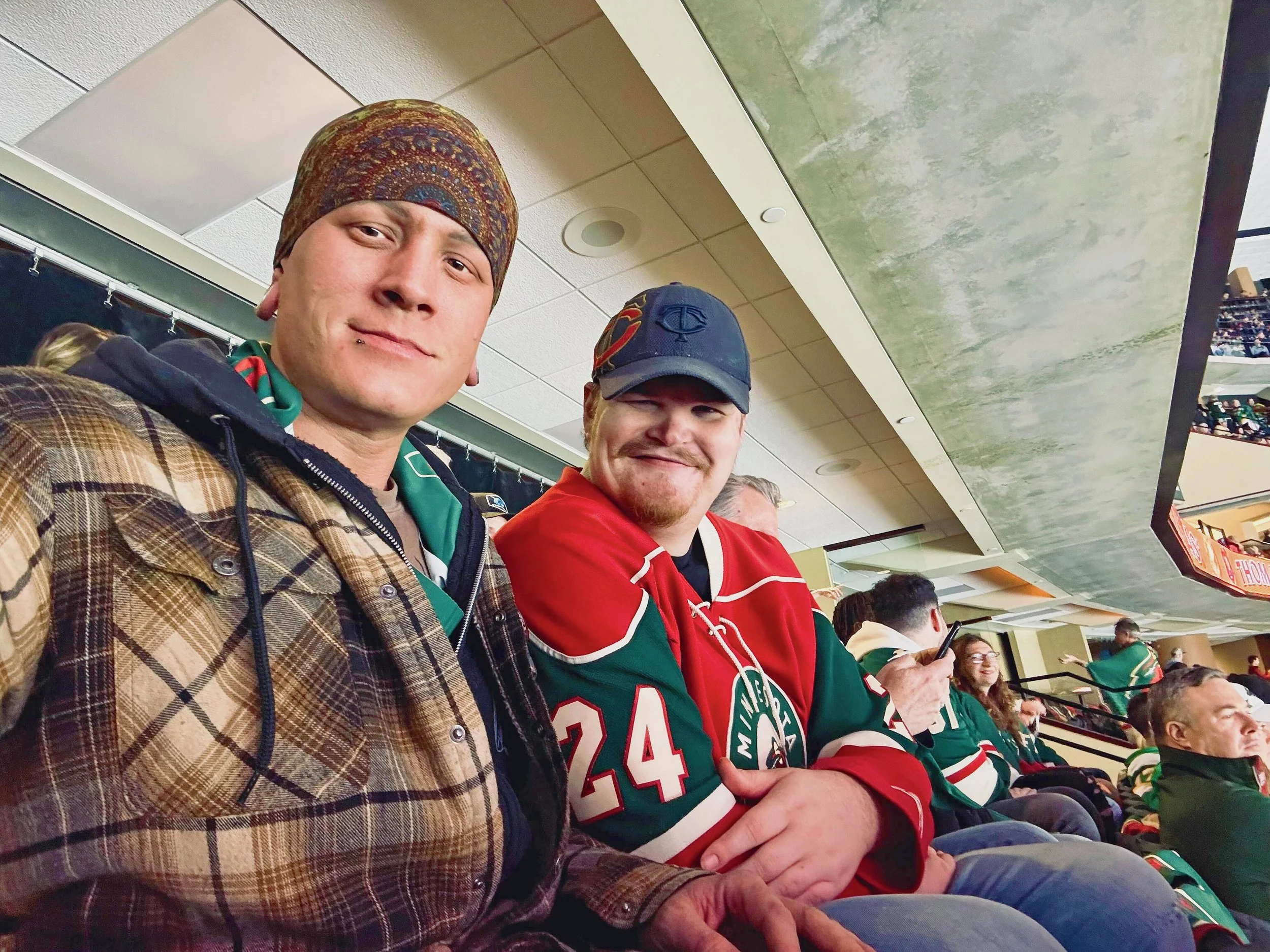 Individuals smiling at a Wild hockey game.