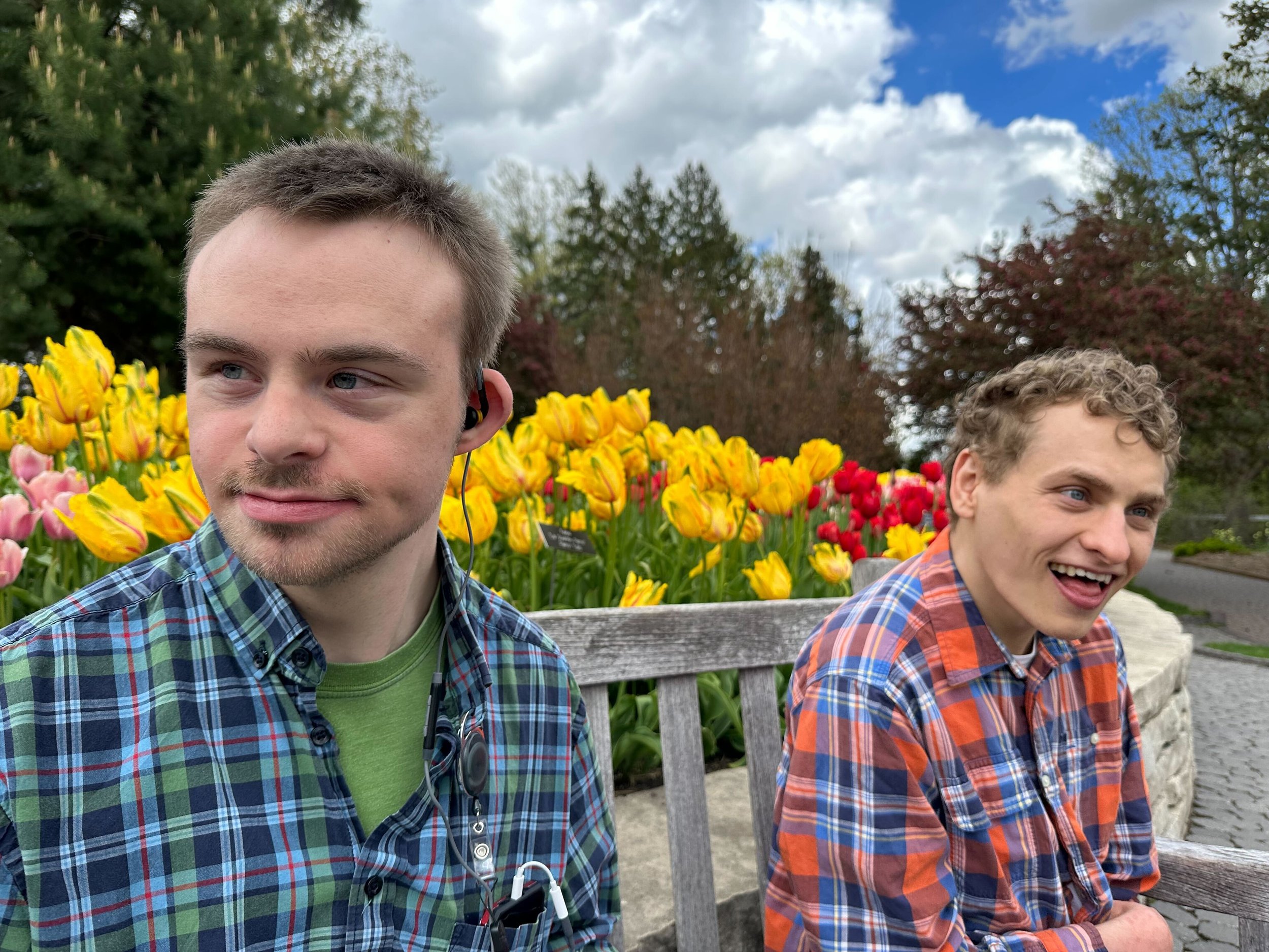 Individuals sitting in front of flowers.