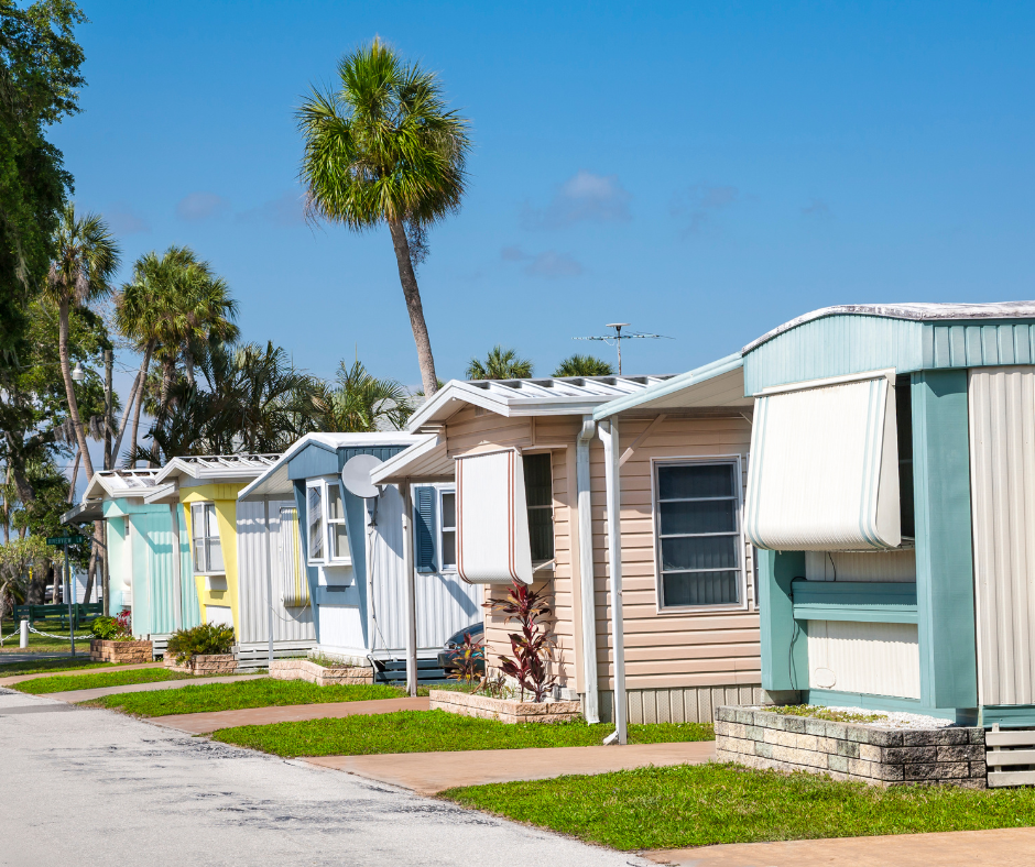 Colorful mobile homes or trailers on a sunny day with palm trees and a blue sky.