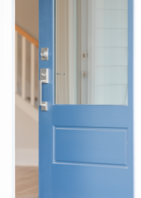 Partially open blue front door with glass panel, metal handle, and lock, showing interior of house with staircase.