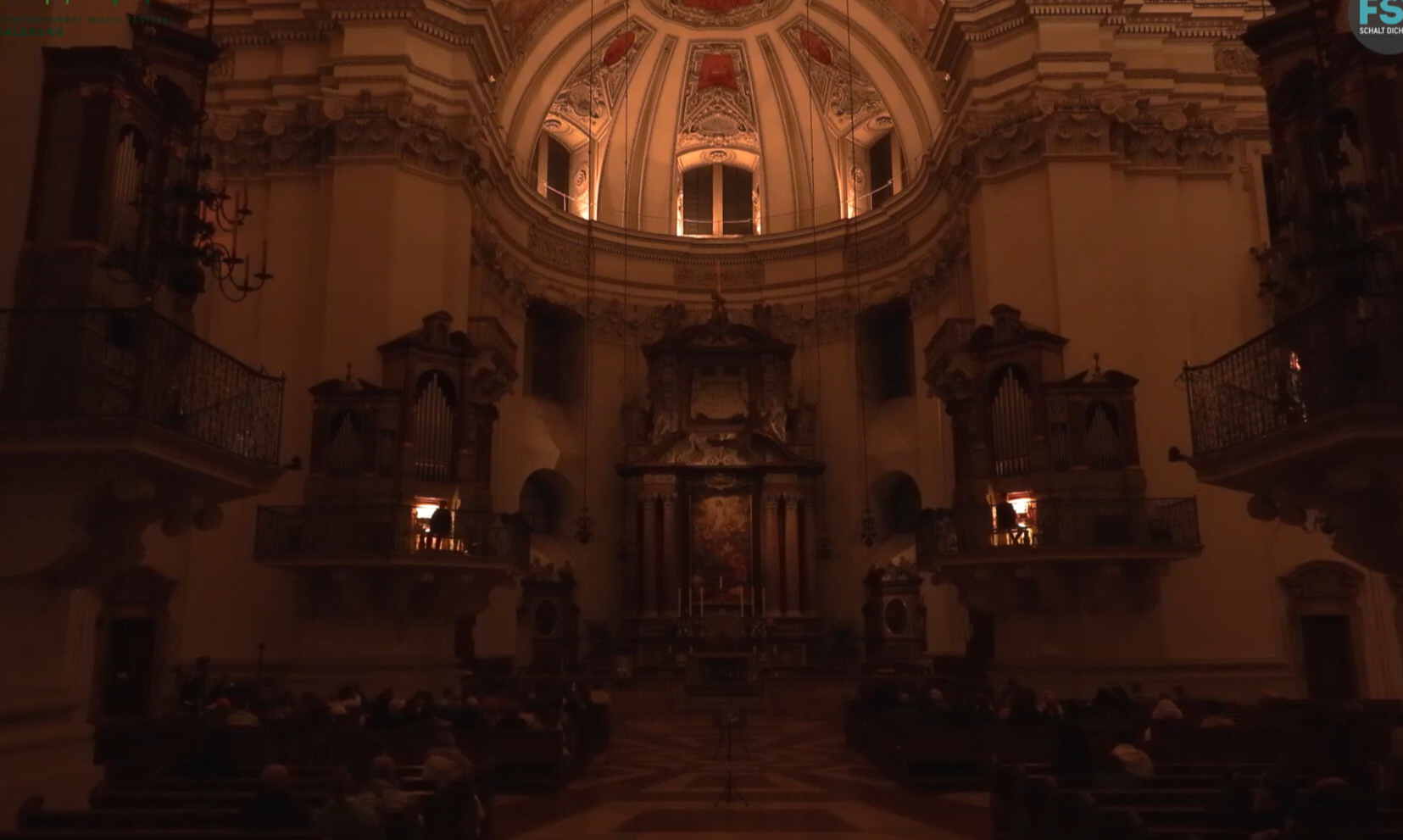 Salzburg Cathedral in November 2025 at the Limina Festival. A dimly lit interior of a historic church or cathedral with ornate architecture, decorative balconies, and a domed ceiling.