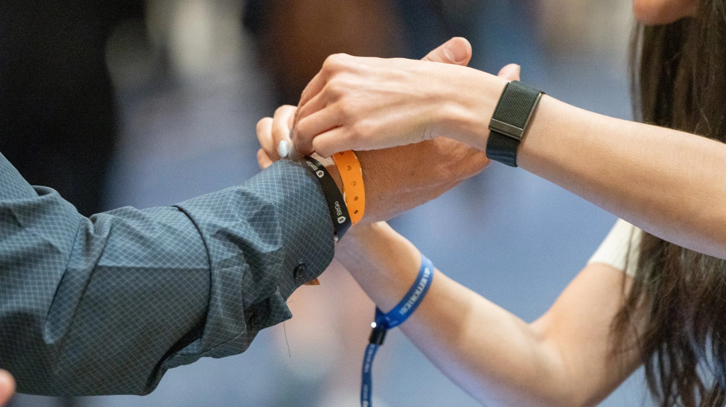Two people holding hands with hospital wristbands, possibly at a medical or health-related event.