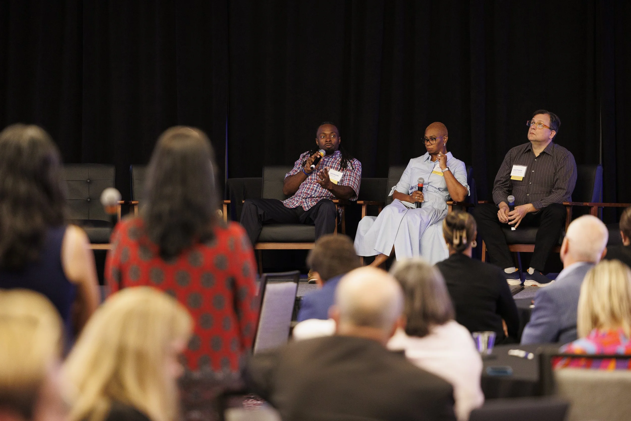 Panel discussion at a conference with four speakers on stage and an audience listening.
