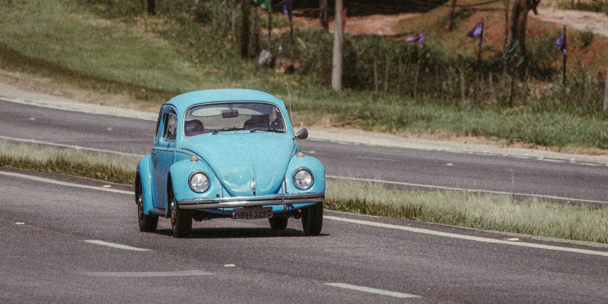 Fusca azul em uma estrada rural.