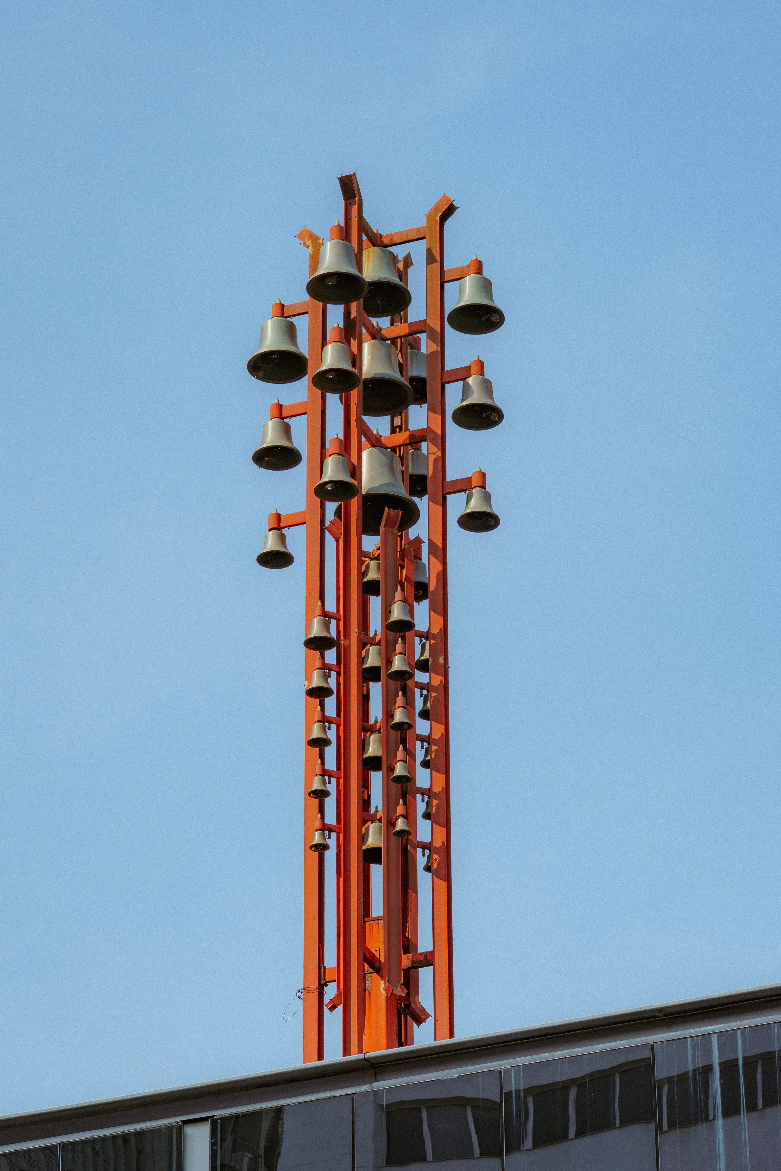 Estrutura de torre de som com várias caixas de som em uma cidade, sob céu claro.