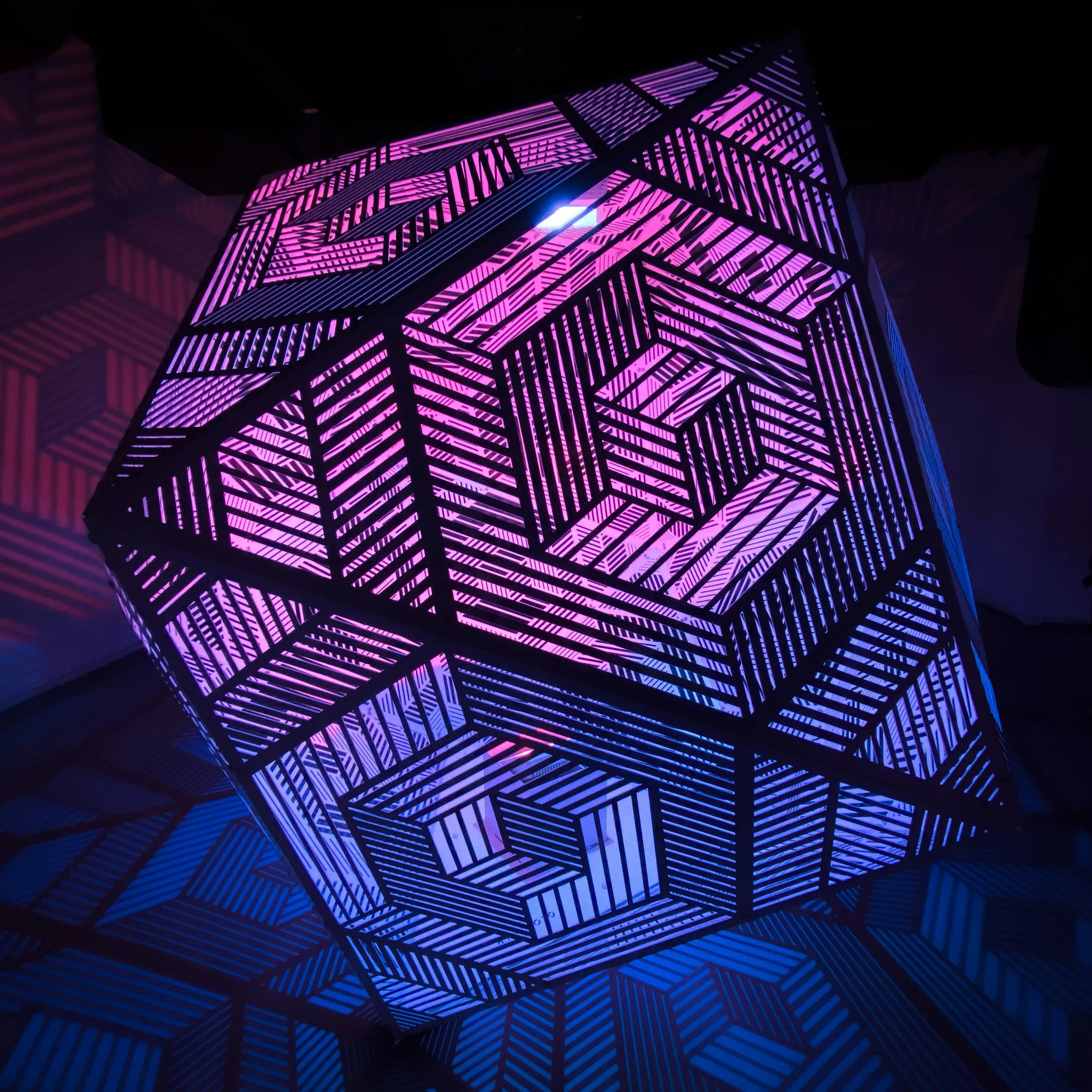 Estrutura geométrica luminosa com linhas em padrões de paralelogramos em cores azul, roxo e rosa.