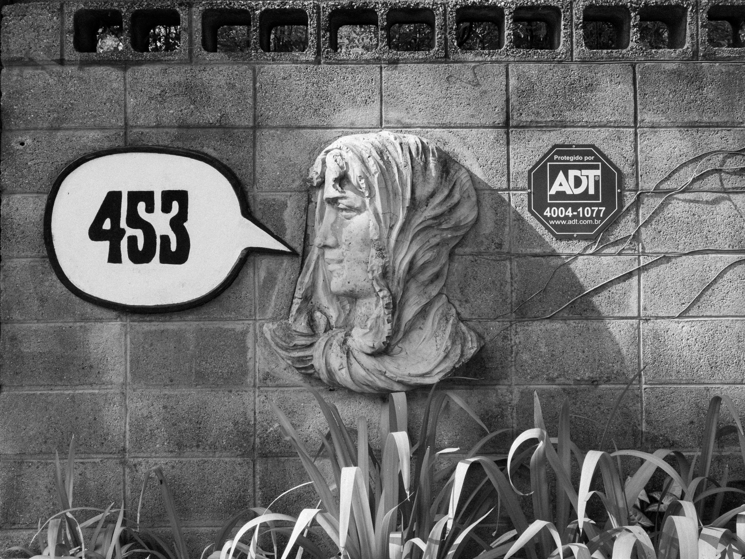 Escultura de uma cabeça de mulher com cabelo longo ao lado de placa de segurança e um balão de fala com '45X'