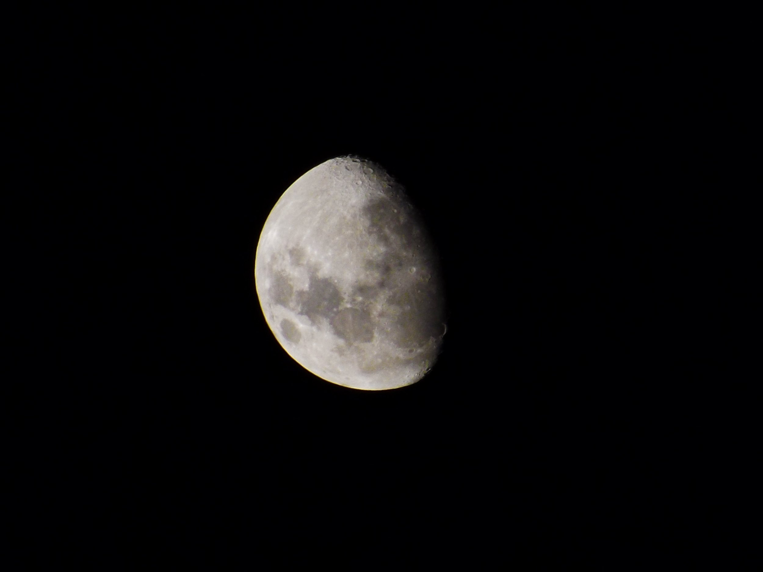 Foto da lua na fase minguante, visível parcialmente, contra fundo preto.