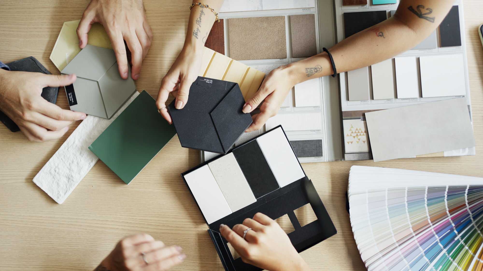 People at a table comparing tile samples in the design process.