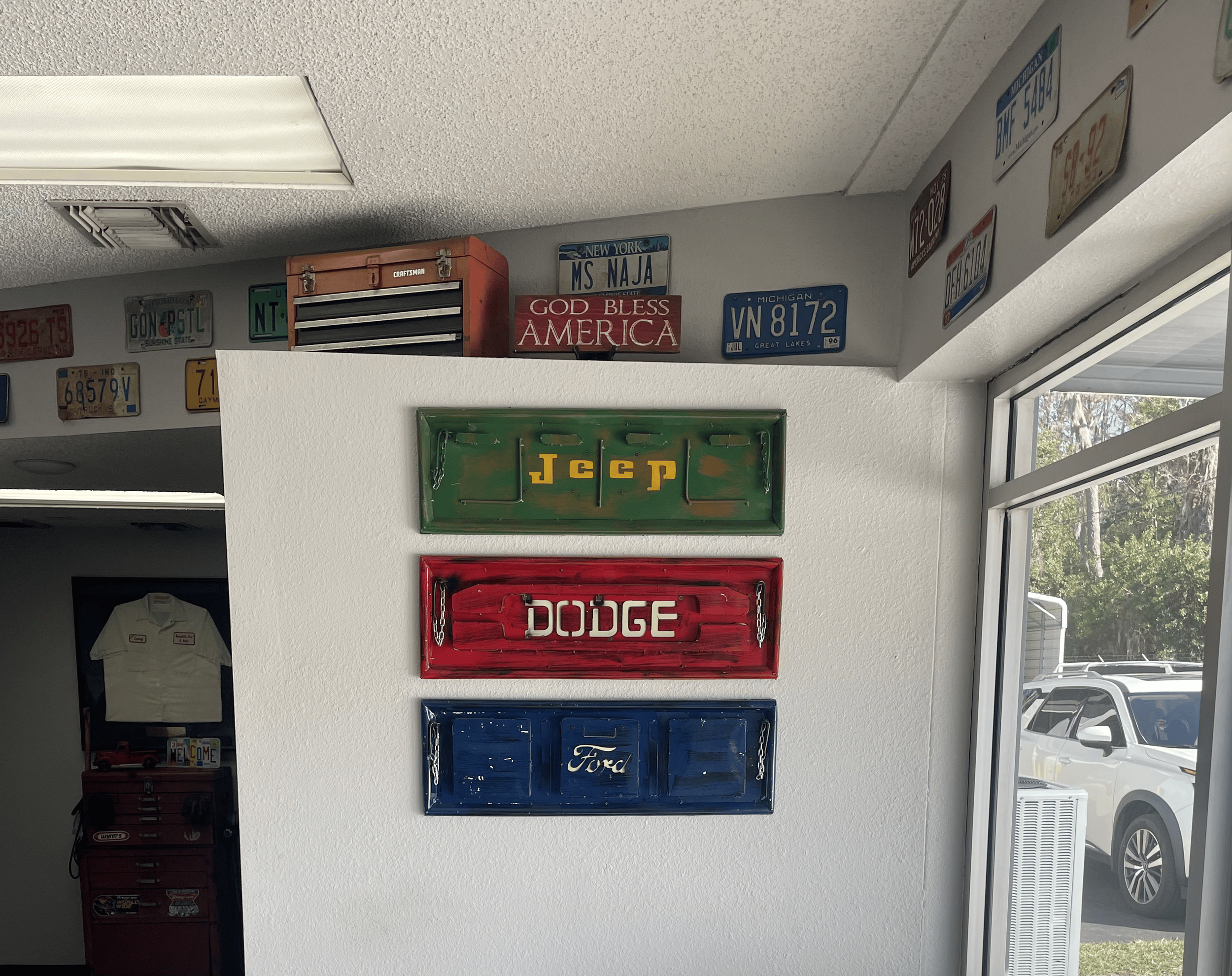 Decorative signs for Jeep, Dodge, and Ford vehicles on a white wall.