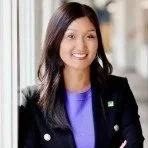 Portrait of a smiling woman with long dark hair wearing a blue top and black blazer.