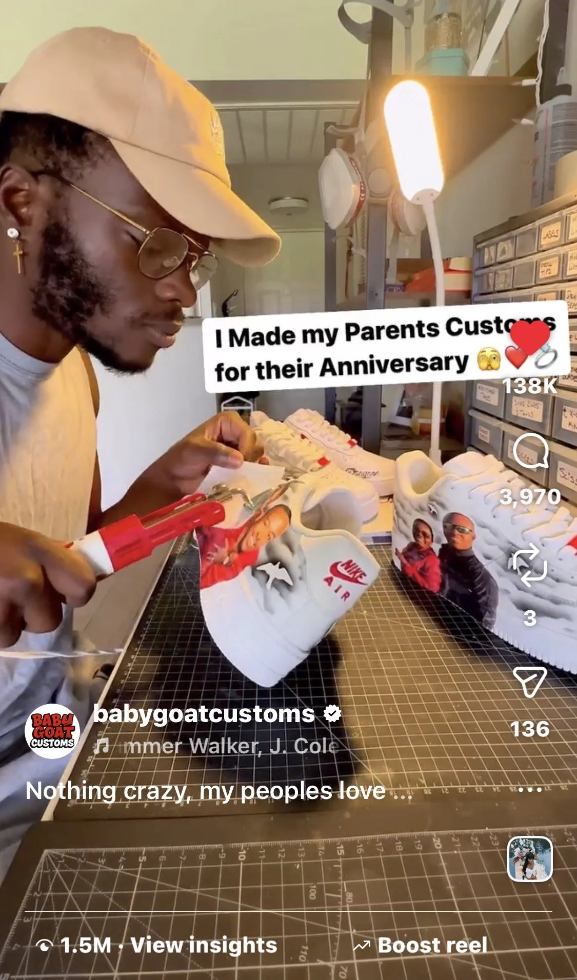 A man wearing glasses, a beige cap, and earrings is customizing a white sneaker with a photo of two people on it, using a hot glue gun. The workspace has a grid cutting mat. Text overlay reads, 'I Made my Parents Customs for their Anniversary' with emojis, and the caption says, 'Nothing crazy, my peoples love...'
