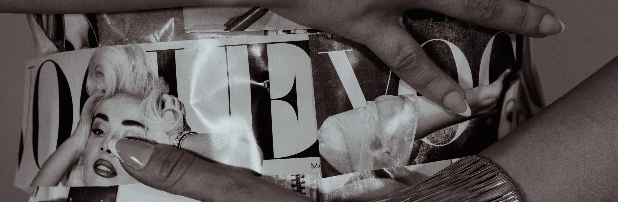 A person holding a magazine with a black-and-white cover featuring a woman with platinum blonde hair, makeup, and jewelry.