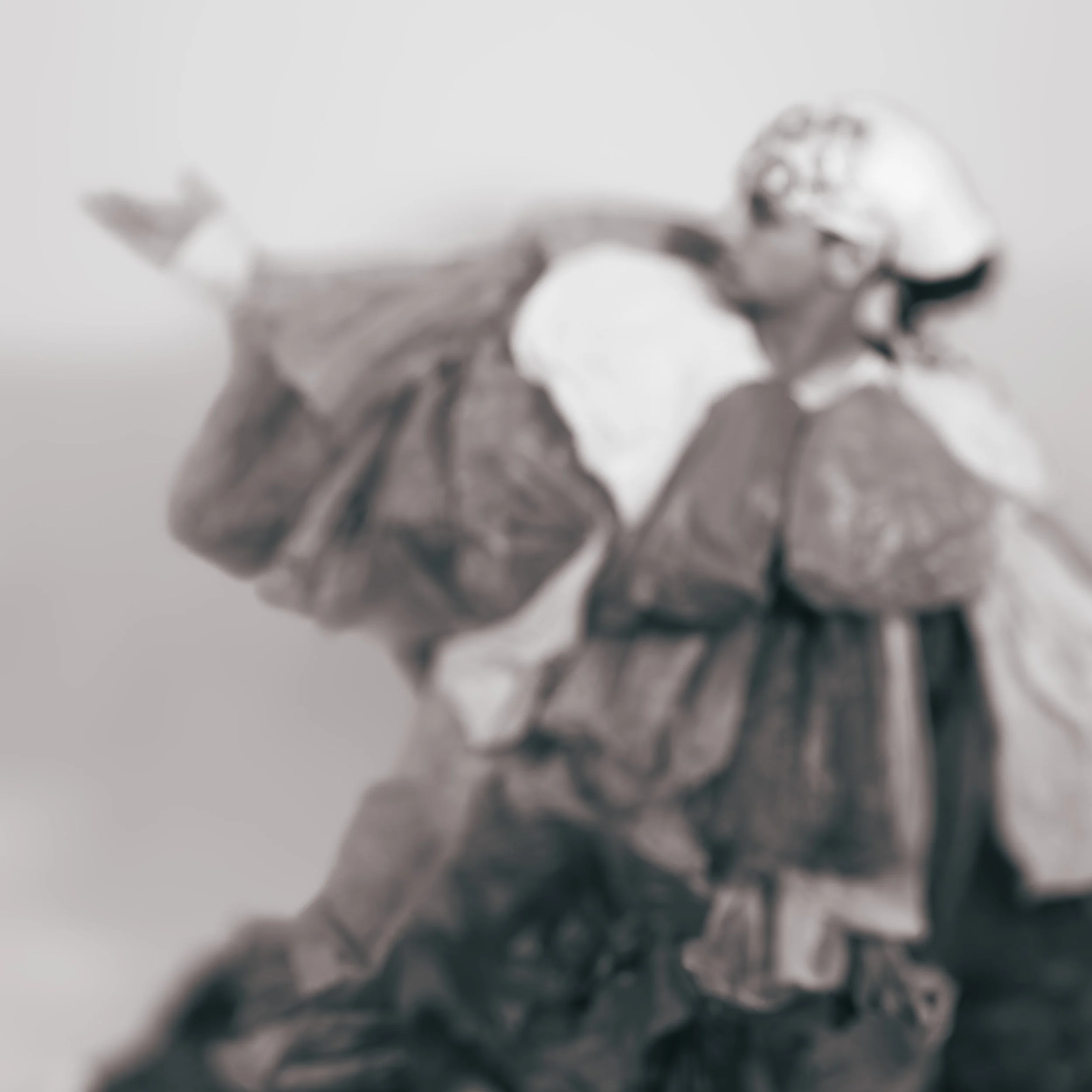 A blurry black and white photograph of a person dressed in grocery bags posing against a white background.