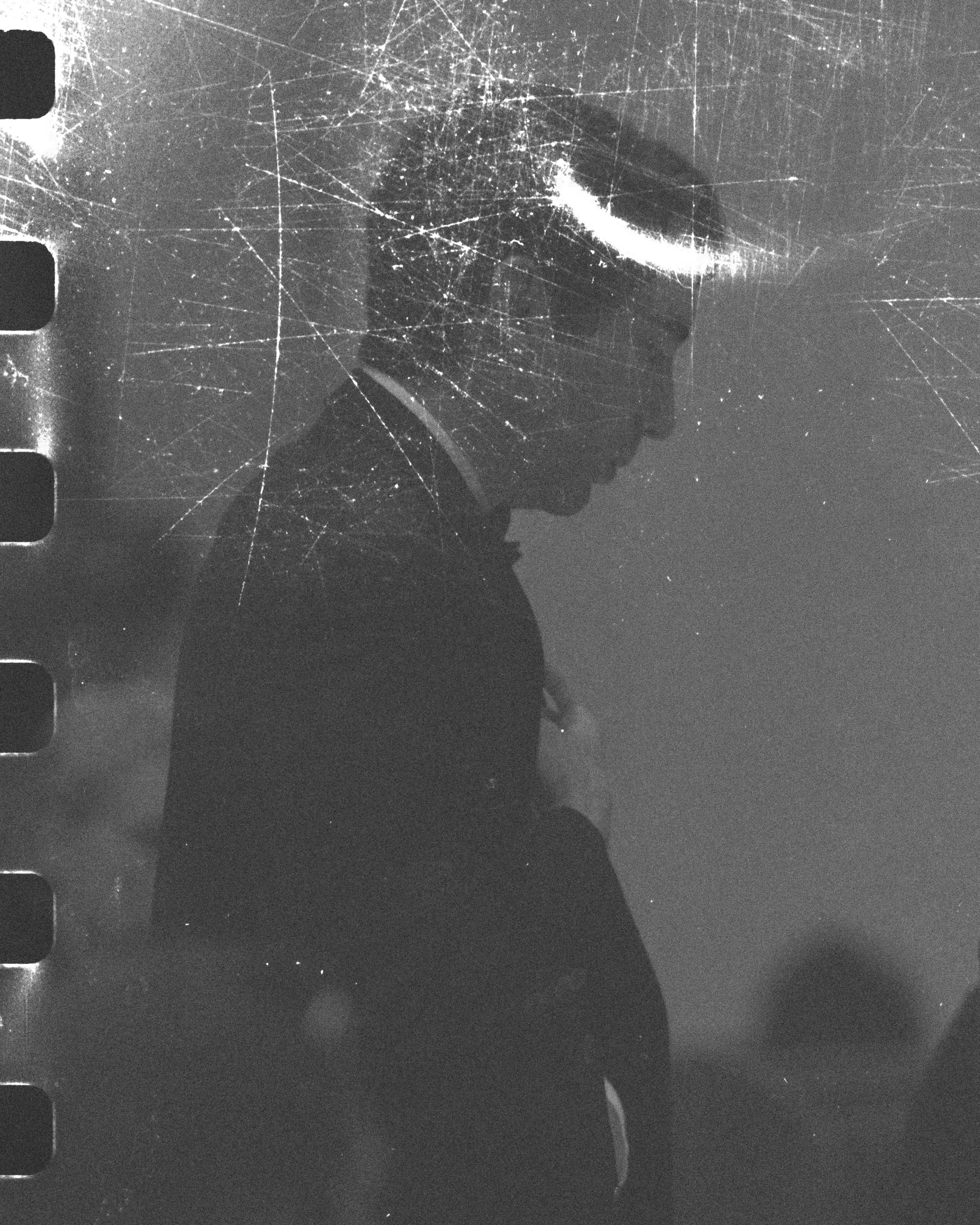 A silhouette of a person with a halo above his head and a film strip on the side in black and white.