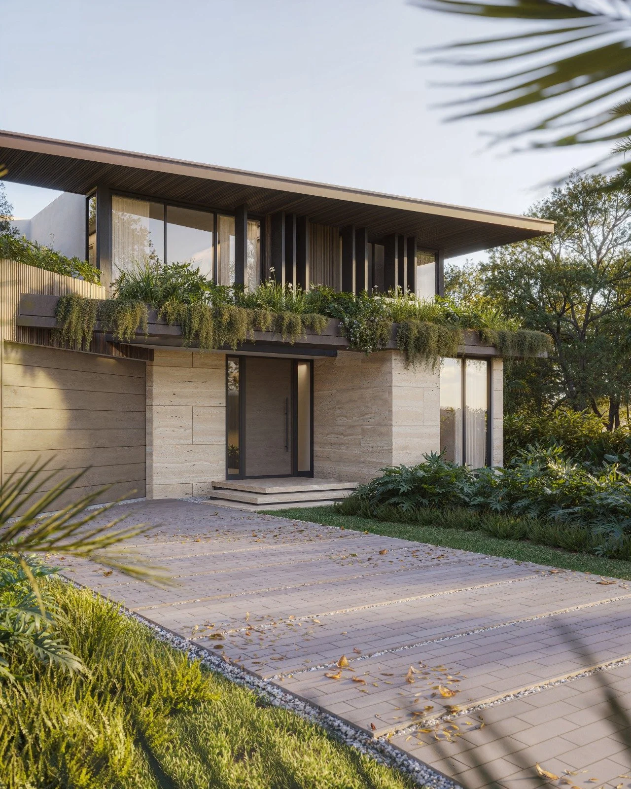 Modern house with beige stone facade, large glass windows, and a lush balcony garden. Paved driveway with fallen leaves, surrounded by greenery and trees.