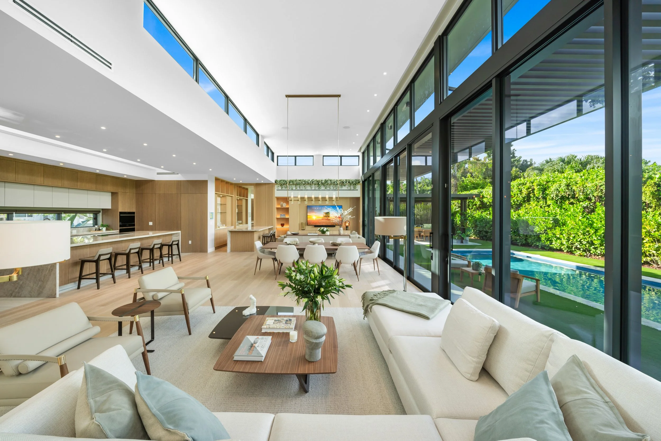 Modern living room with large glass windows overlooking a backyard with a pool and garden.