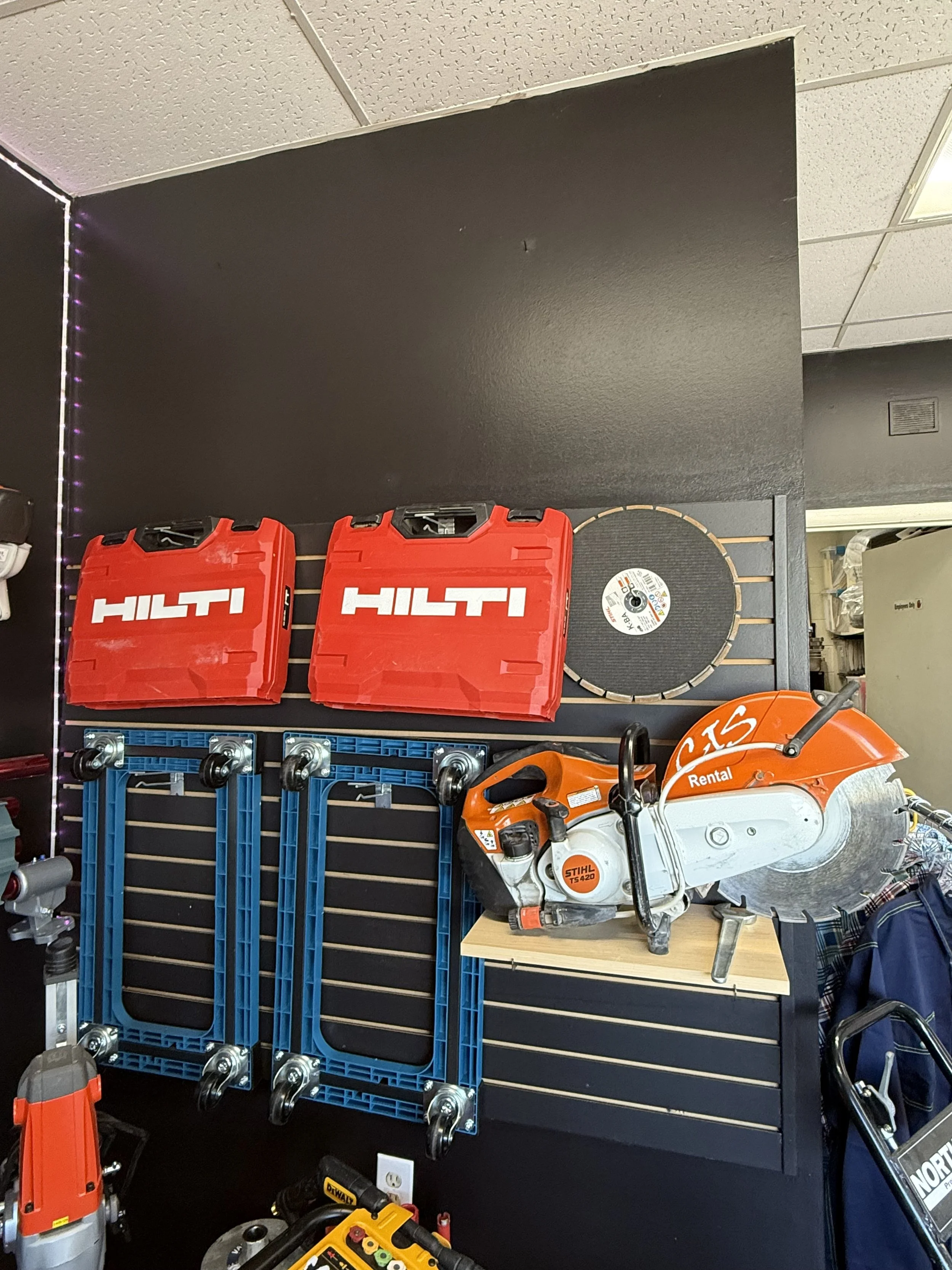 Wall display with red Hilti cases, a large circular saw, and blue frame brackets.