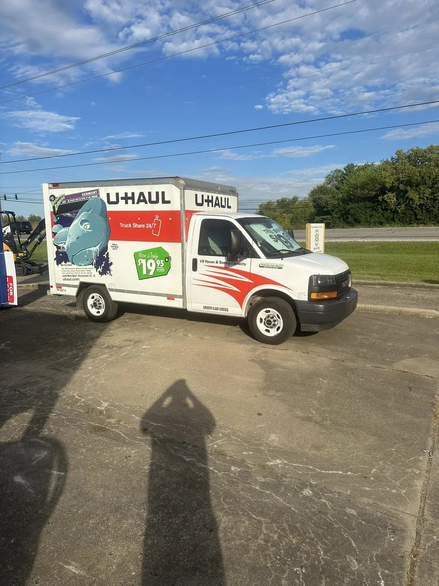 U-Haul moving truck parked on concrete, featuring rental price and a fish graphic, under blue sky with clouds.