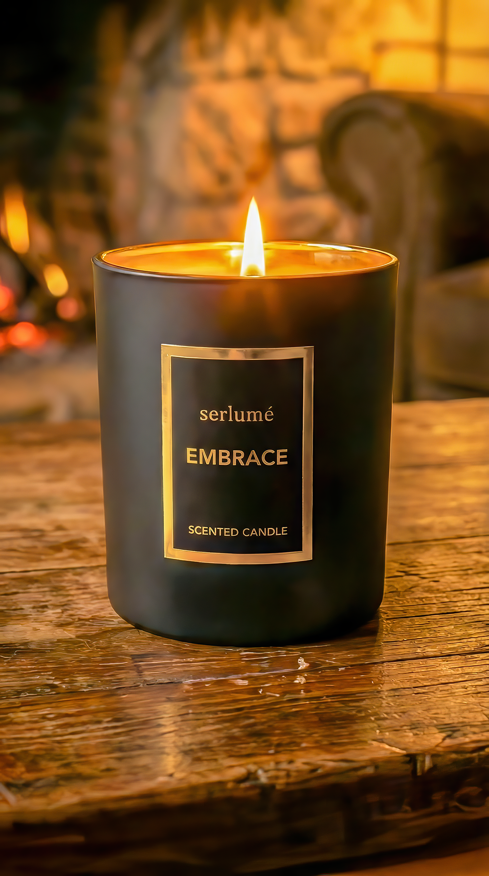 A black scented candle with a burning flame on a wooden surface. The candle is labeled 'serlumé EMBRACE Scented Candle'.