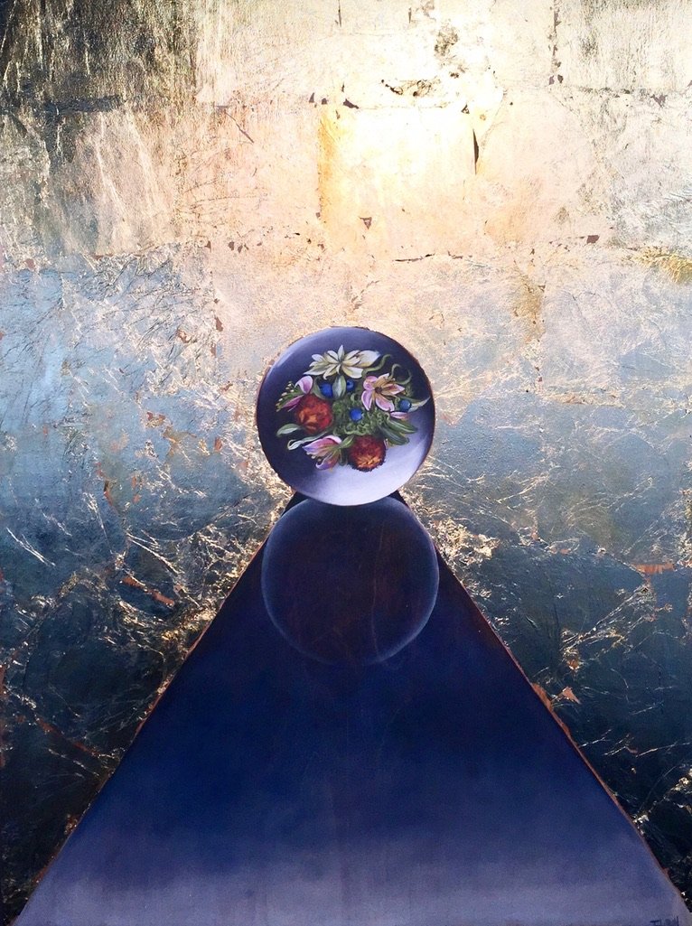 A decorative glass ball with a floral design, placed on a dark triangular surface, with a gold-textured wall background.