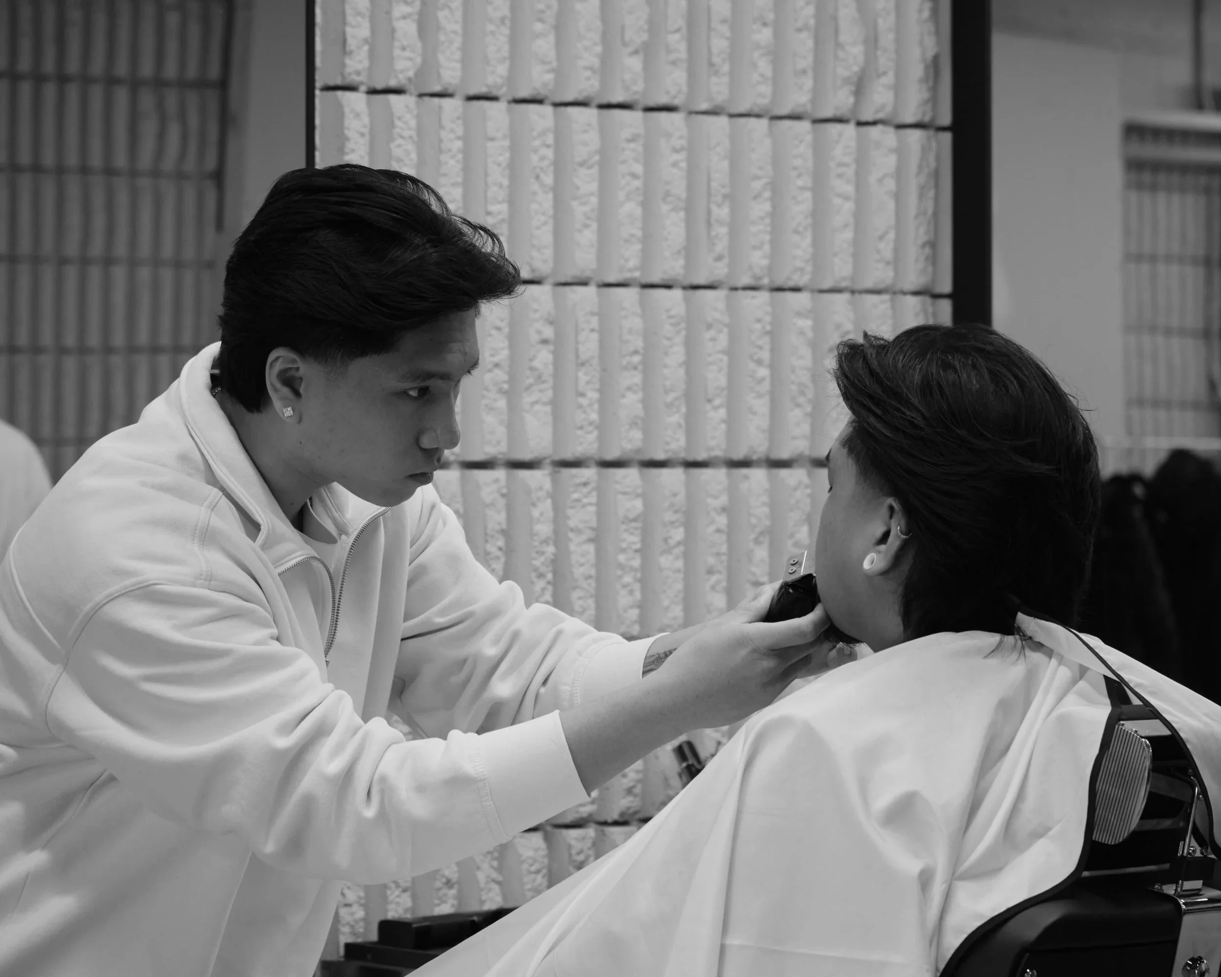 Winnipeg barber trimming a client’s facial hair, with client facing away from the camera.