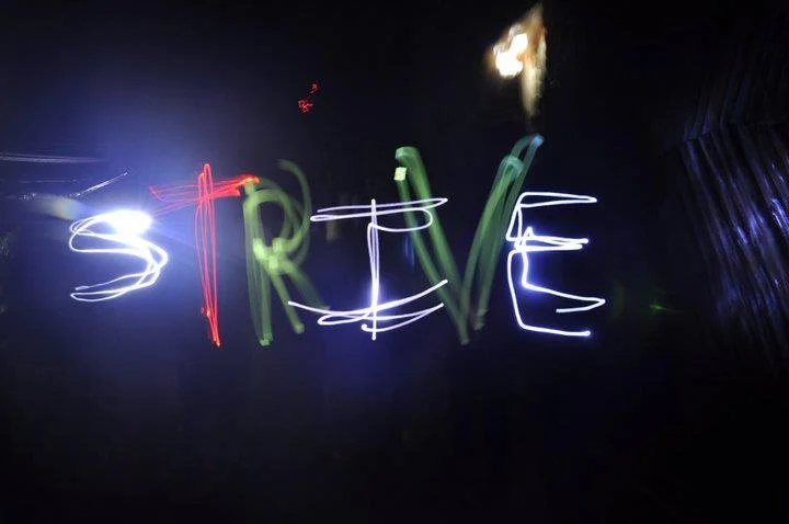 Light painting spelling out the word 'STREVE' against a dark background with streaks of colorful light, including white, green, red, and purple.