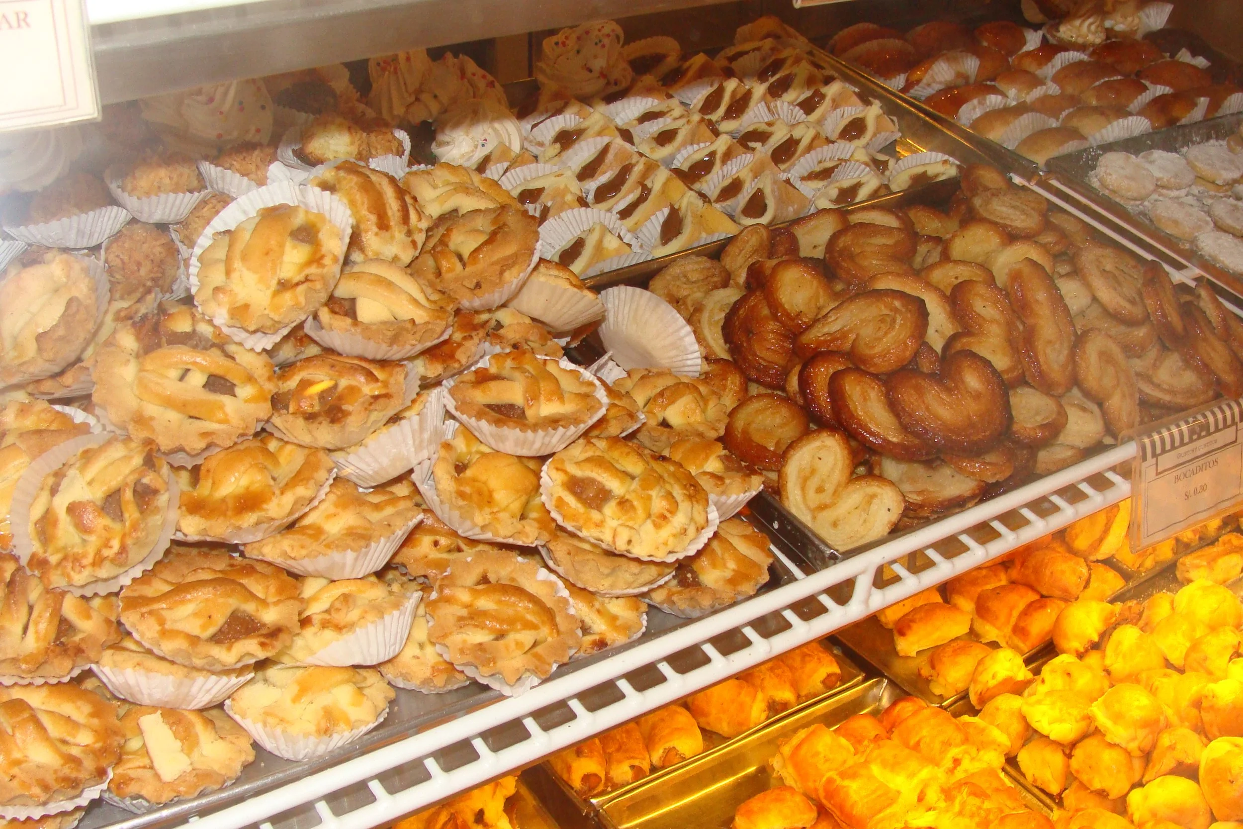 Various baked pastries including small pies, cinnamon rolls, and custard tarts displayed in a bakery case.