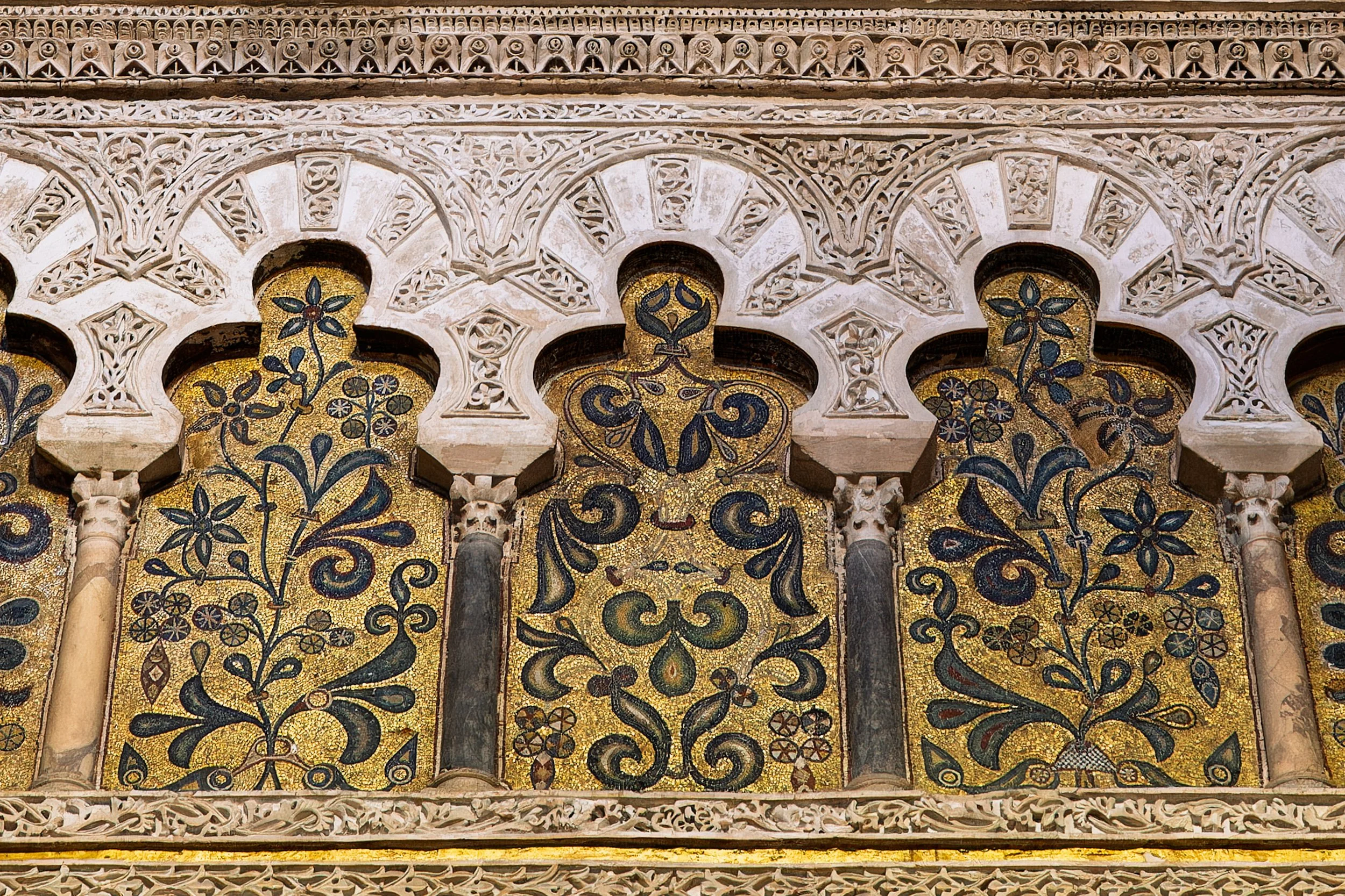 Close-up of ornate architectural details with floral mosaic patterns and intricate carved stonework.