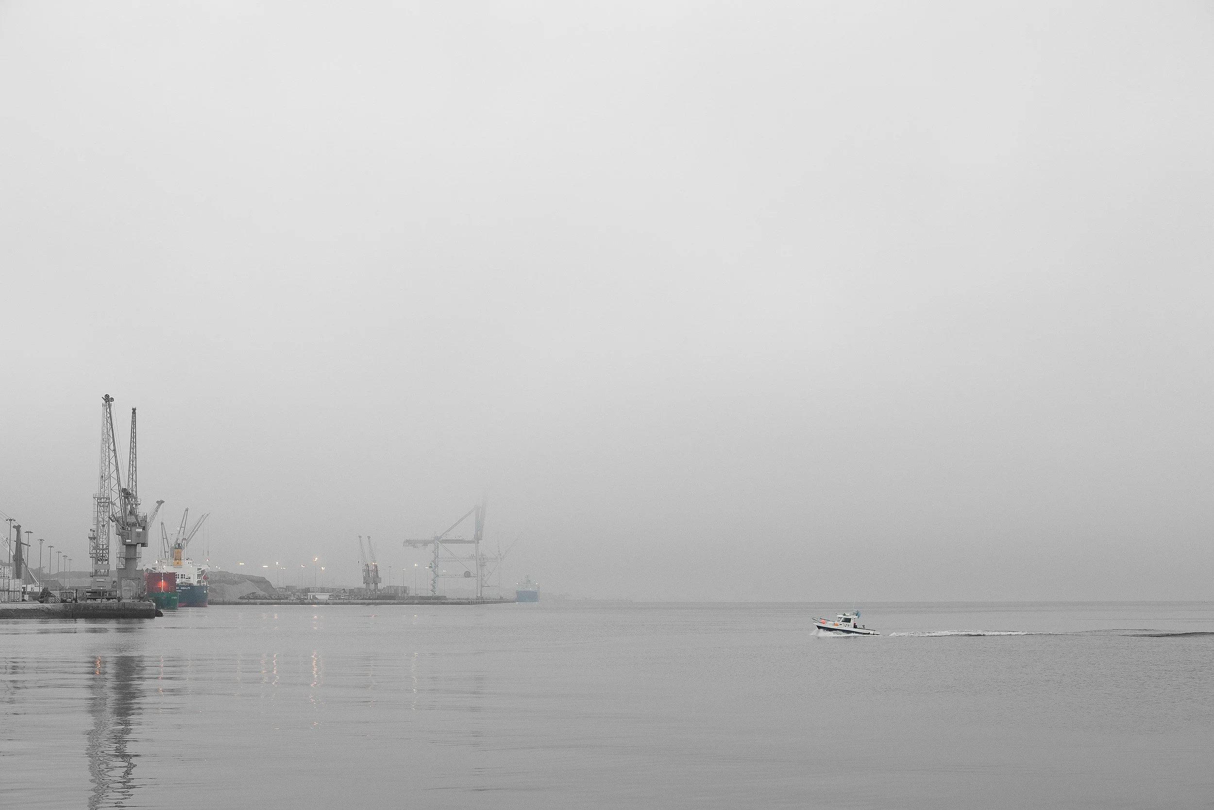As the morning light touches the estuary, a pilot boat approaches the quay in the port of Setúbal, Portugal. Just south of Lisbon, Setúbal is a major maritime hub with a rich naval tradition and industrial importance. This photo captures the pilot bo