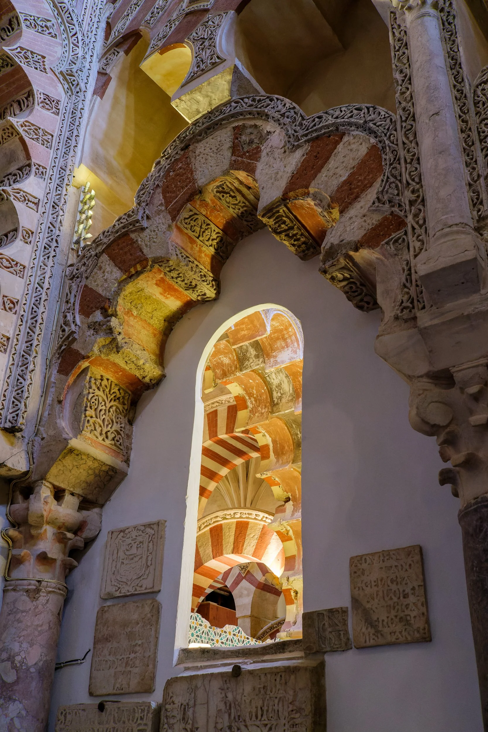 A series of ornate, multicolored arches inside a historic building, showcasing intricate architectural details and decorative patterns.