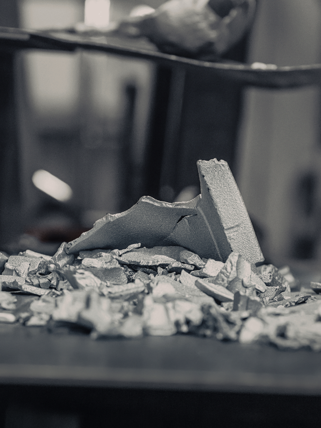 Broken pieces of aluminium on a surface, with a blurred background.