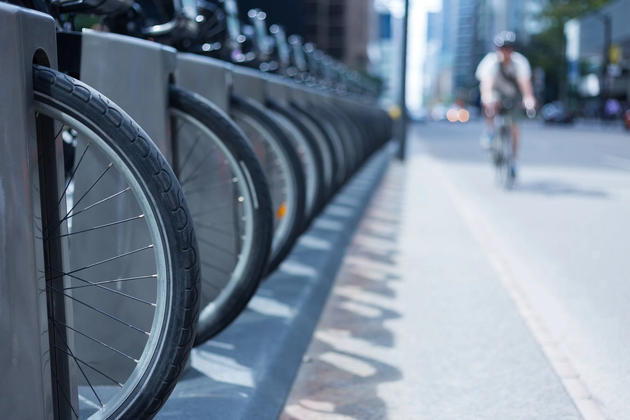 Row of urban bicycles docked in metal bike-sharing stands using precision-cast components.