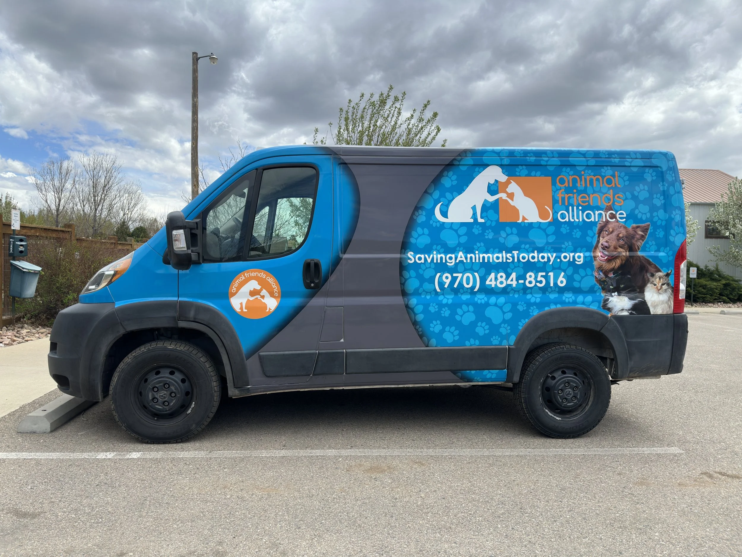 A blue and gray contractor van with an animal rescue organization's branding. The side features the Animal Friends Alliance logo, website "SavingAnimalsToday.org," phone number, and images of a dog and a cat.