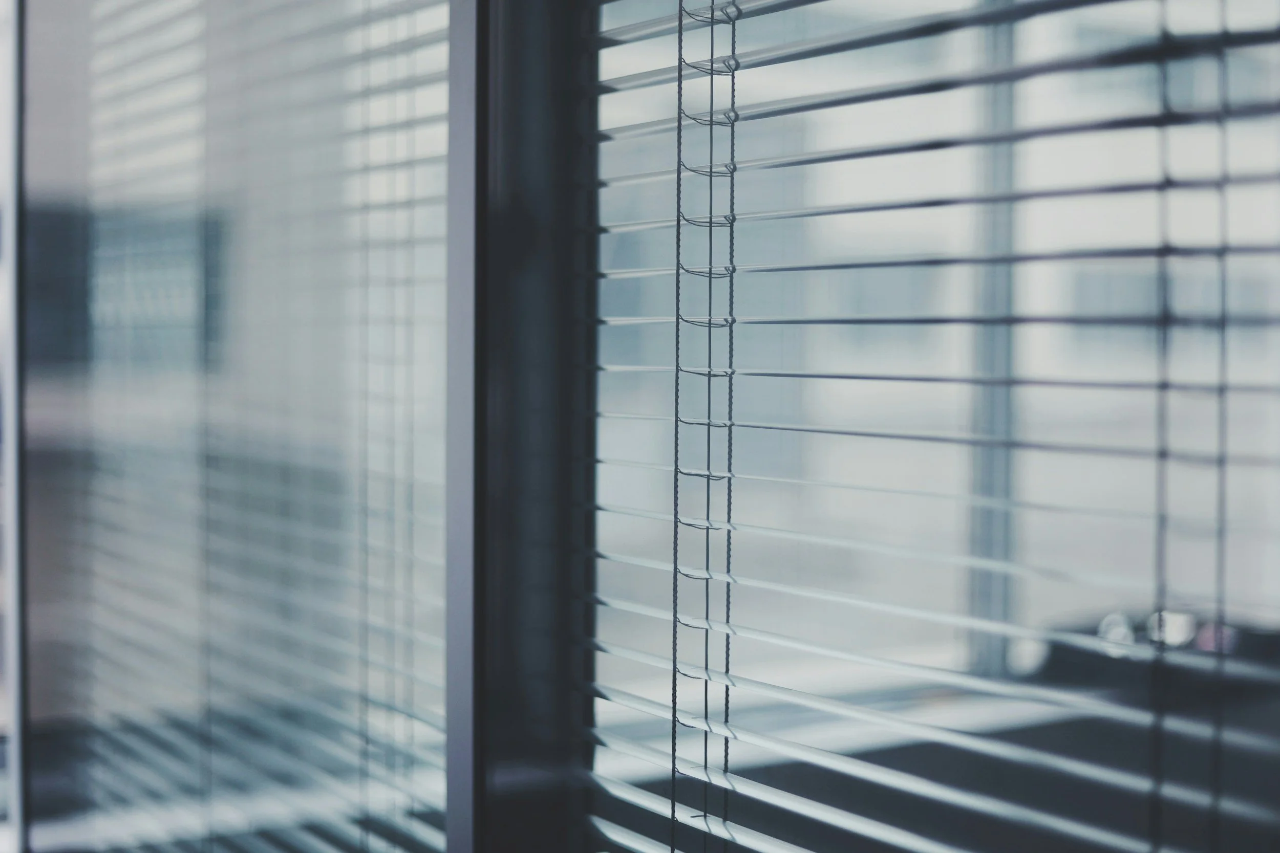 Close-up of window blinds inside a room with sunlight filtering through.