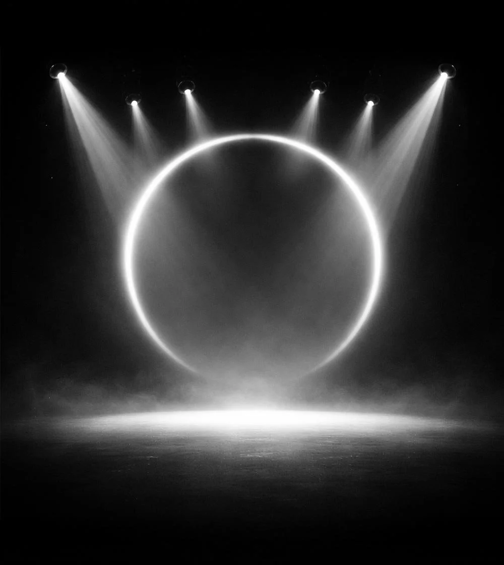 Stage with four spotlights shining down on a glowing, circular light projection in the center, creating a minimalist and abstract lighting display.