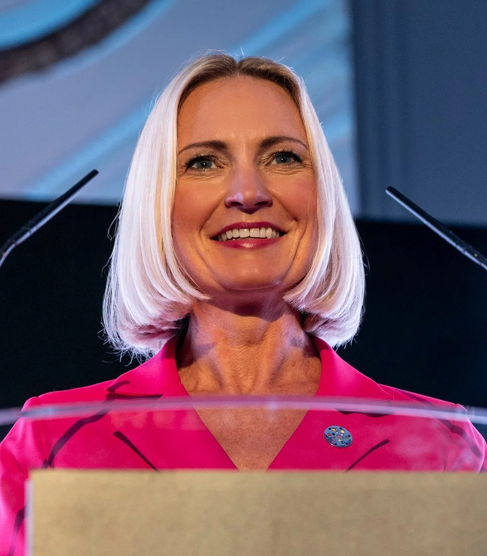 Heidi Mallace smiling while speaking at a podium.