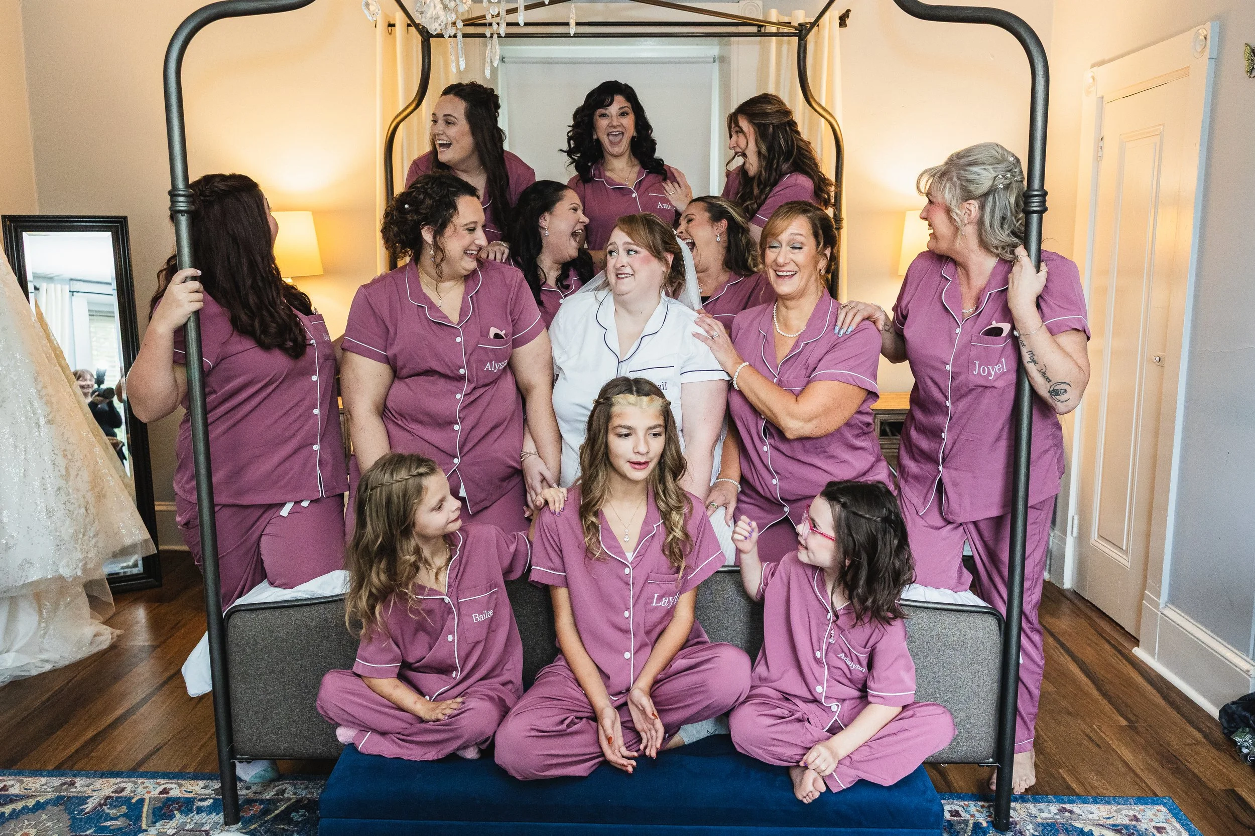 Brides and bridesmaids on bed posing while getting ready