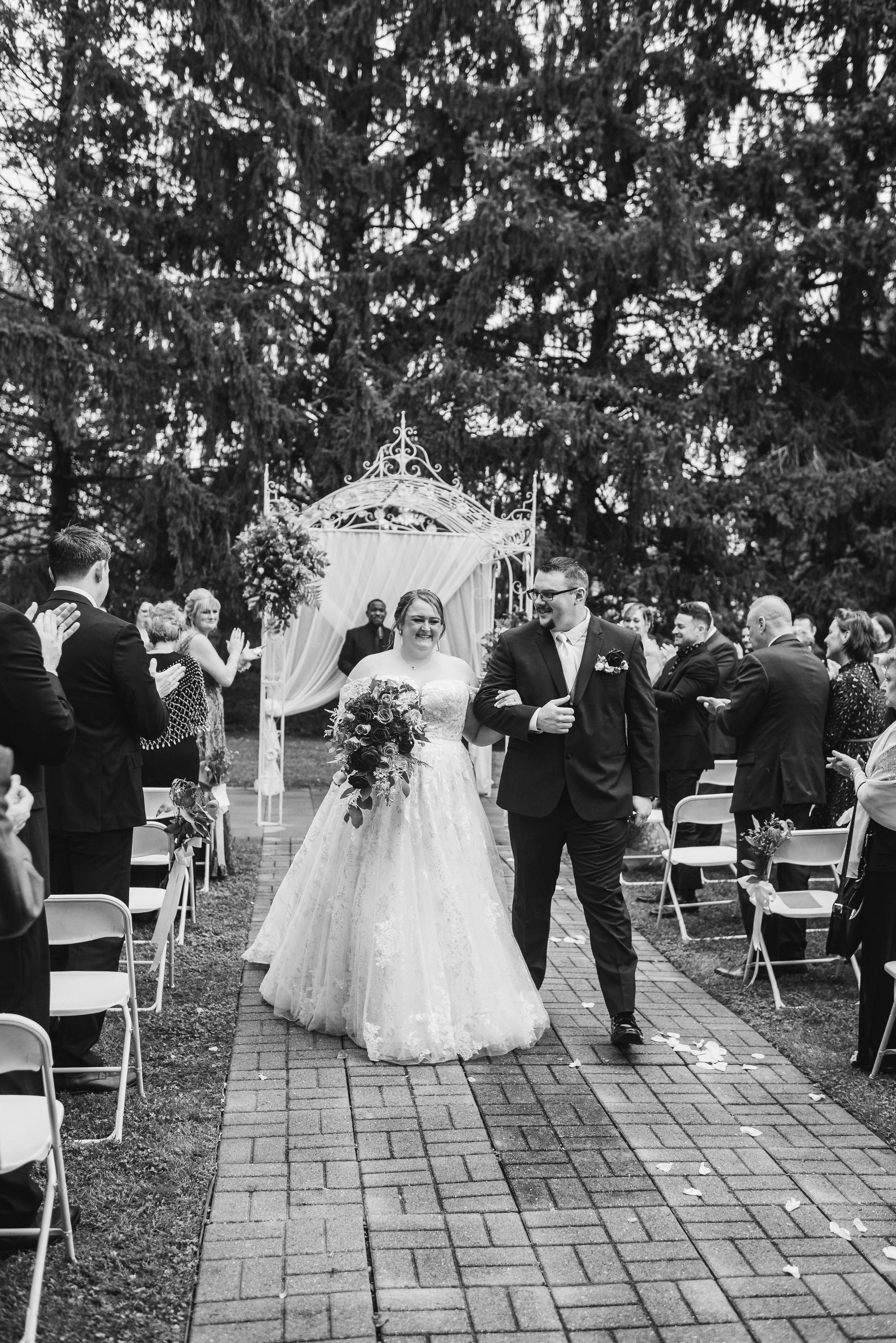Wedding couple walking down garden aisle