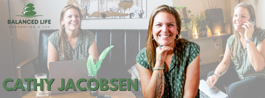 Three women sitting at a table in a cozy office, smiling and laughing. One is on the phone, another is resting her chin on her hand, and the third is looking at the camera. There is a laptop and a glass of water on the table, with plants and artwork in the background.