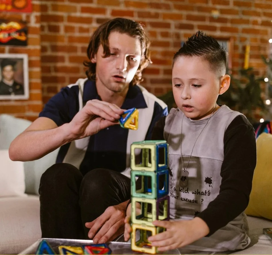 A young boy works with his therapist to finish a magnet tower.