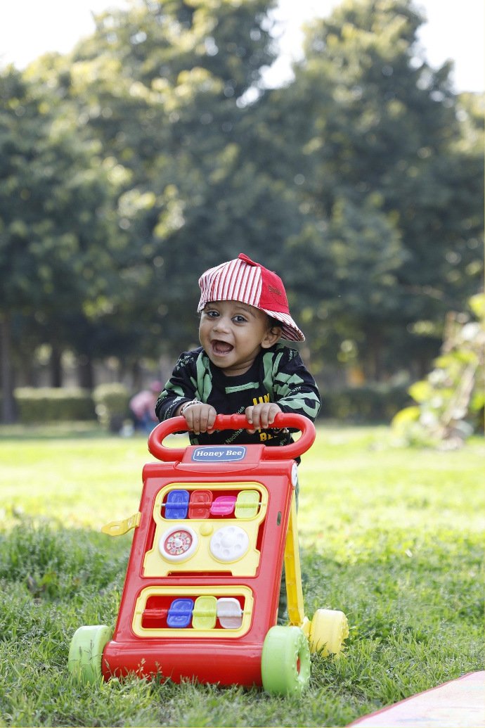A boy plays with a toy cart in a park.