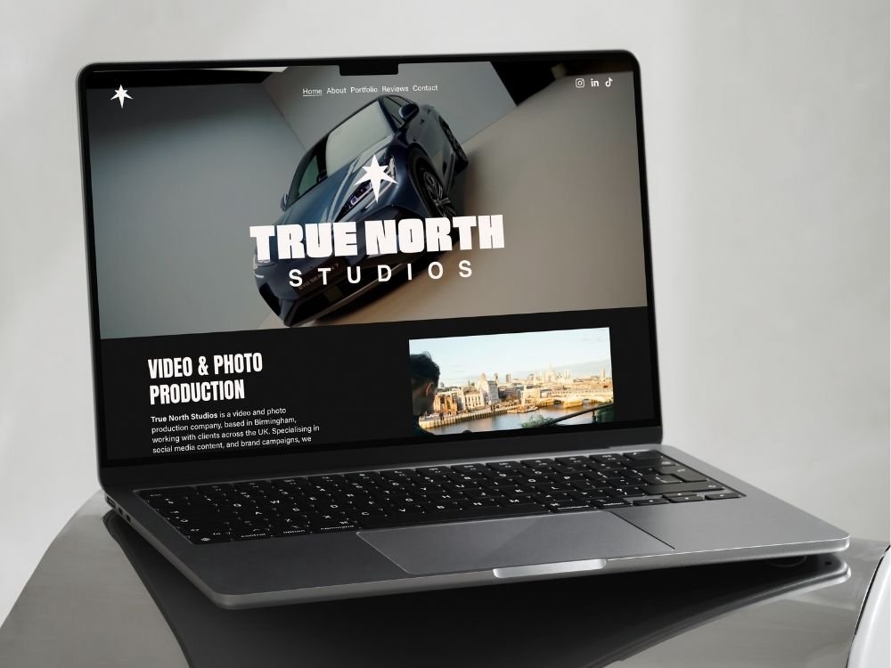 Open laptop displaying the website for True North Studios, a video and photo production company, with a large image of a car and cityscape.